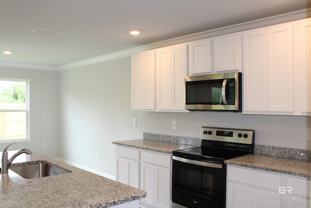 kitchen with appliances with stainless steel finishes, a sink, white cabinetry, and crown molding