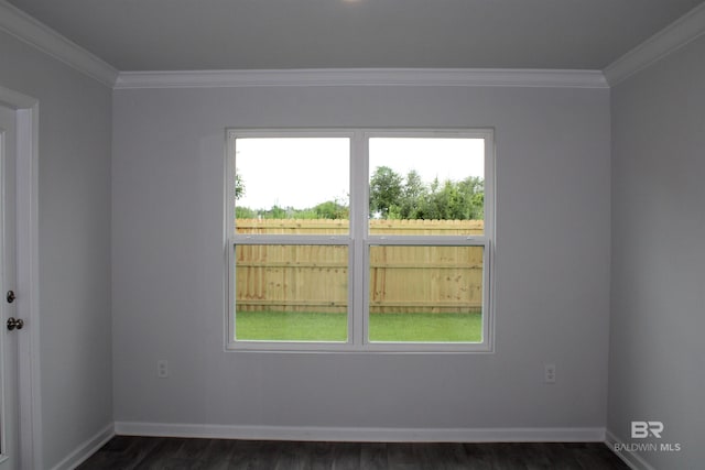 empty room featuring dark wood-style floors, crown molding, and baseboards