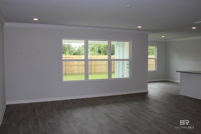 spare room featuring dark wood finished floors, crown molding, and baseboards