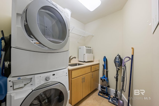 laundry area featuring stacked washer / dryer, cabinets, sink, and light tile floors