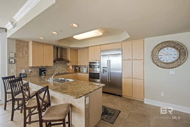 kitchen with kitchen peninsula, appliances with stainless steel finishes, light tile flooring, wall chimney range hood, and a kitchen bar