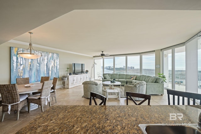 tiled dining space with ceiling fan and crown molding