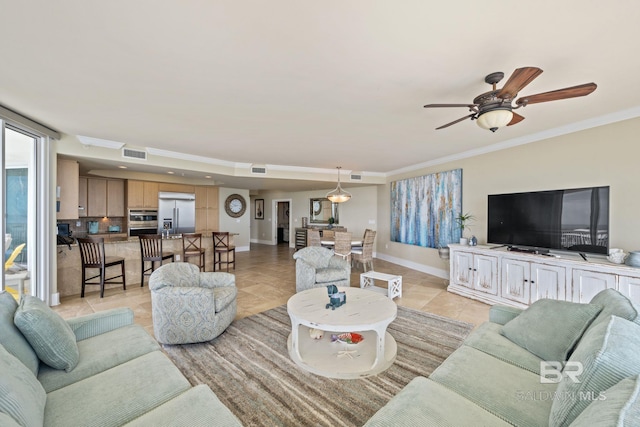 tiled living room with ceiling fan and crown molding