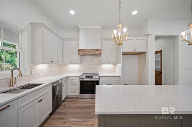 12380 Mannich Ln, Foley, AL 36580 - kitchen with appliances with stainless steel finishes, wall chimney range hood, a sink, a chandelier, and recessed lighting
