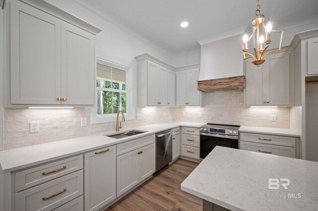 12380 Mannich Ln, Foley, AL 36580 - kitchen with stainless steel appliances, a sink, custom exhaust hood, wood finished floors, and a chandelier