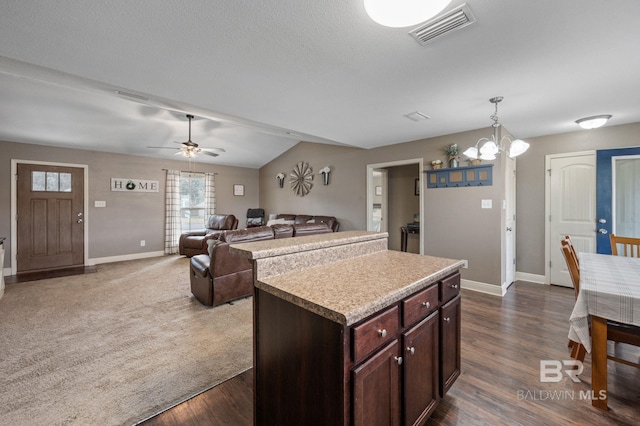 kitchen with pendant lighting, a center island, ceiling fan with notable chandelier, and dark wood-type flooring