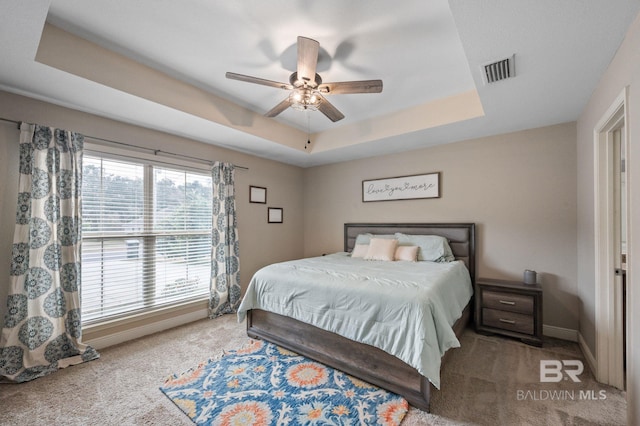 bedroom featuring carpet floors, ceiling fan, and a tray ceiling