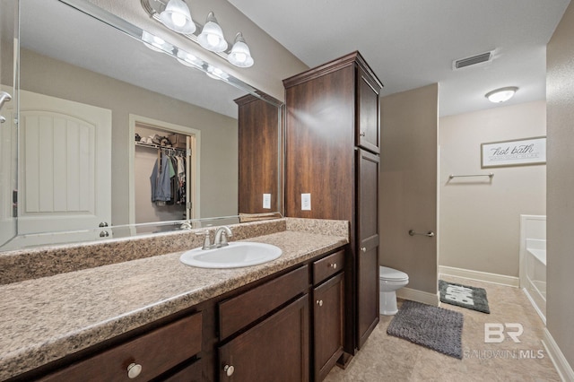 bathroom featuring toilet, a washtub, tile patterned flooring, and vanity