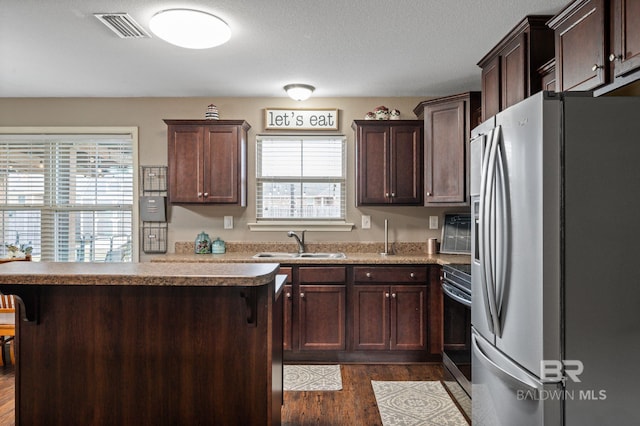 kitchen featuring dark hardwood / wood-style floors, stainless steel appliances, a breakfast bar, dark brown cabinets, and sink