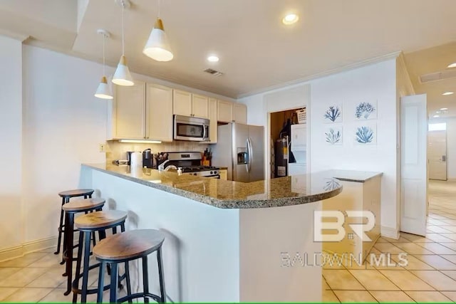 kitchen with a breakfast bar, light tile patterned floors, stainless steel appliances, decorative backsplash, and a peninsula