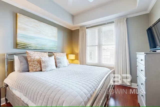 bedroom featuring crown molding, a tray ceiling, and dark wood-style flooring