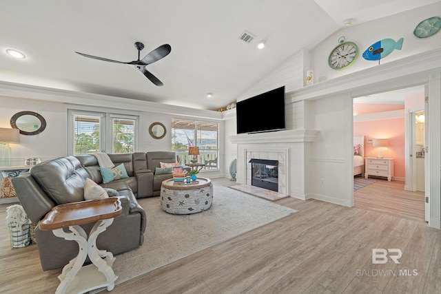 living room with ceiling fan, a fireplace, vaulted ceiling, and light hardwood / wood-style flooring