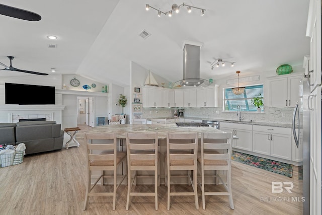 kitchen with light stone counters, island range hood, a center island, and white cabinets