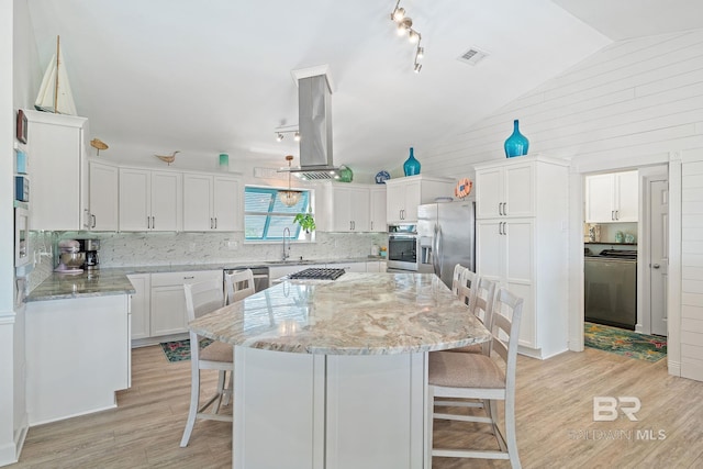 kitchen with vaulted ceiling, a kitchen island, appliances with stainless steel finishes, island range hood, and white cabinets