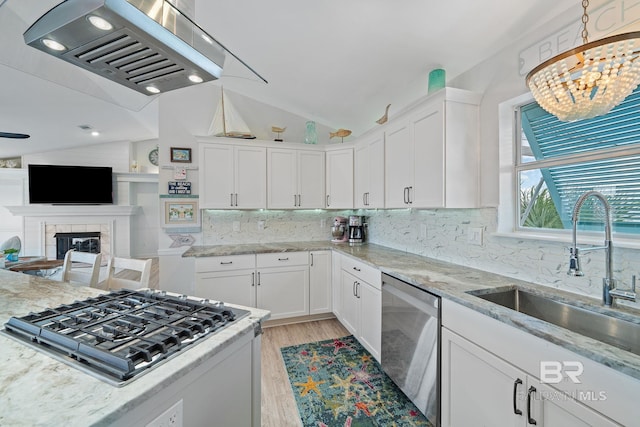 kitchen with appliances with stainless steel finishes, sink, white cabinets, and range hood