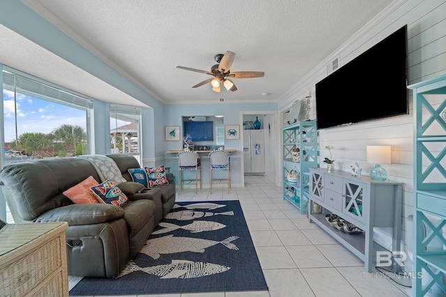 tiled living room with ceiling fan, ornamental molding, and a textured ceiling