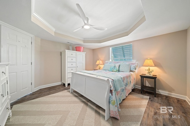 bedroom featuring a raised ceiling, ornamental molding, hardwood / wood-style flooring, and ceiling fan