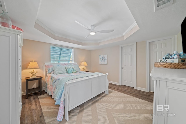 bedroom featuring a tray ceiling, ornamental molding, light hardwood / wood-style floors, and ceiling fan