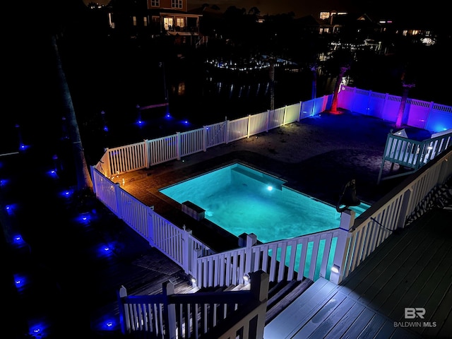 pool at night with a wooden deck