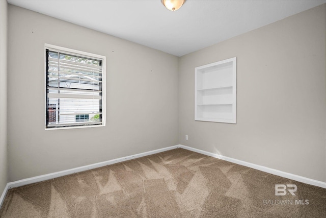 carpeted spare room featuring built in features