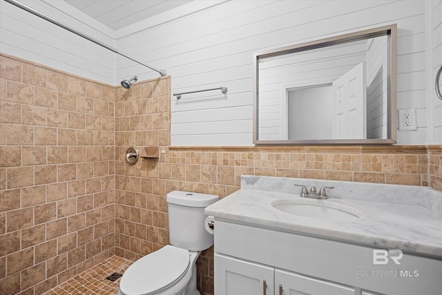 bathroom featuring vanity, toilet, tile walls, and tiled shower