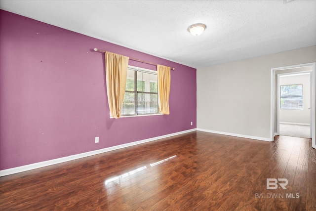 spare room with a textured ceiling and dark hardwood / wood-style floors