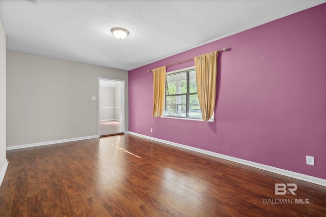 spare room with a textured ceiling and dark hardwood / wood-style flooring