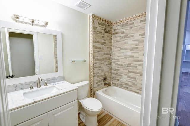 full bathroom featuring tiled shower / bath, vanity, and toilet