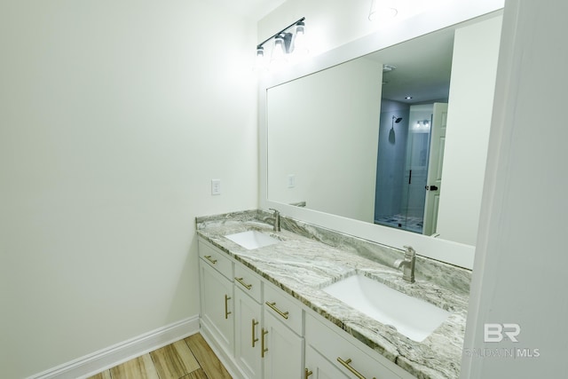 bathroom with a shower with shower door, large vanity, and double sink