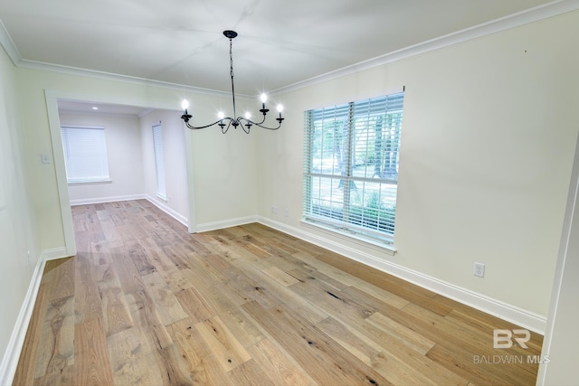 empty room with ornamental molding, light hardwood / wood-style flooring, and a chandelier