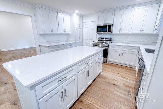 kitchen featuring stainless steel appliances, a center island, tasteful backsplash, and light hardwood / wood-style flooring