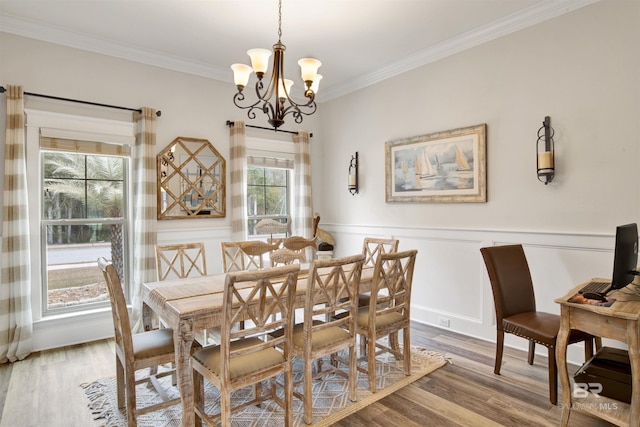 dining room with wood-type flooring, a notable chandelier, and crown molding