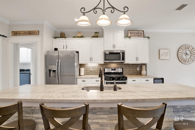 kitchen with pendant lighting, appliances with stainless steel finishes, crown molding, and sink