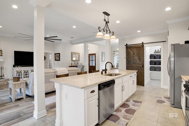 kitchen featuring sink, hanging light fixtures, stainless steel appliances, a barn door, and a kitchen island with sink