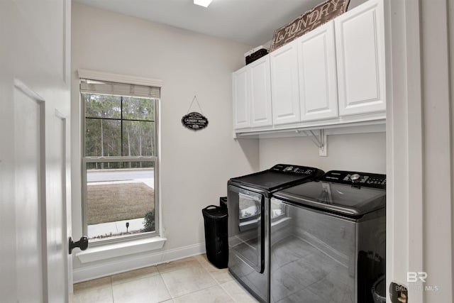 laundry room featuring separate washer and dryer, light tile patterned floors, and cabinets