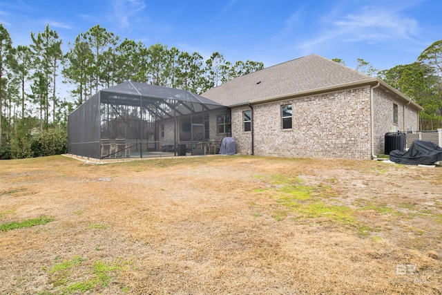 rear view of house with cooling unit, a pool, a lawn, and glass enclosure