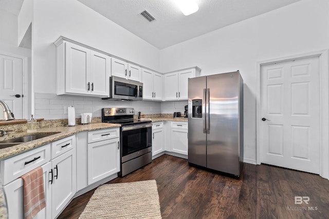 kitchen with light stone countertops, appliances with stainless steel finishes, sink, and white cabinets