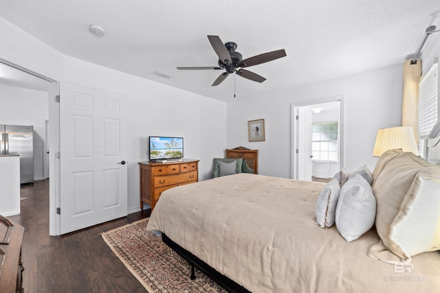 bedroom with stainless steel refrigerator, ceiling fan, dark hardwood / wood-style floors, and a textured ceiling