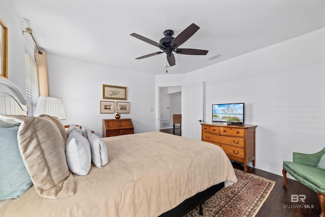 bedroom with ceiling fan, hardwood / wood-style floors, and a textured ceiling