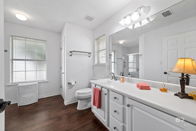 bathroom with hardwood / wood-style flooring, vanity, a shower with shower door, and toilet