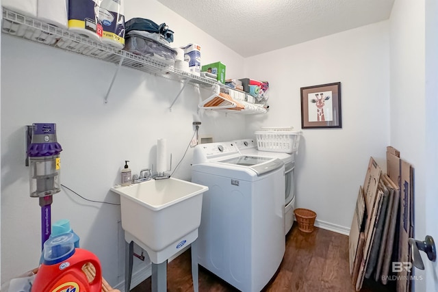 washroom with dark wood-type flooring, sink, a textured ceiling, and washer and clothes dryer