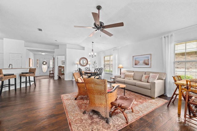 living room with dark wood-type flooring, ceiling fan with notable chandelier, and vaulted ceiling