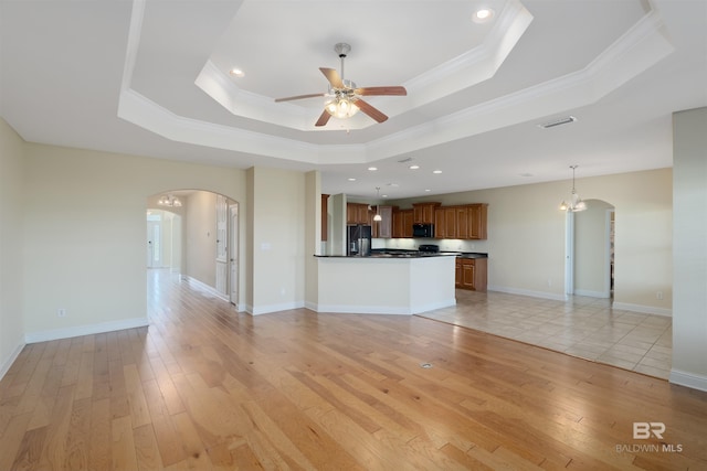 unfurnished living room with ornamental molding, a tray ceiling, light wood-type flooring, and ceiling fan