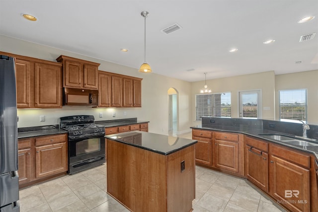 kitchen with black appliances, a center island, sink, pendant lighting, and a notable chandelier