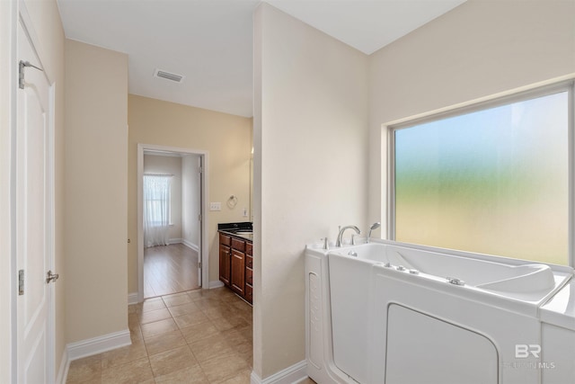 bathroom with tile patterned floors, a tub, and vanity