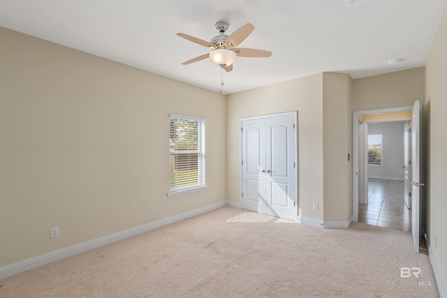 unfurnished bedroom featuring ceiling fan, a closet, and light colored carpet