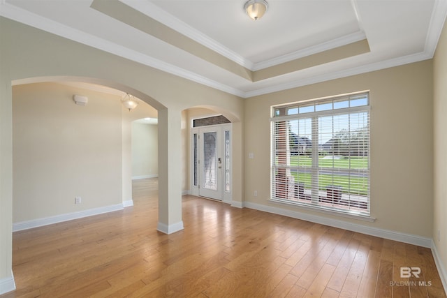 spare room with french doors, ornamental molding, a tray ceiling, and light hardwood / wood-style floors