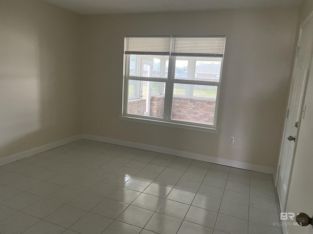 spare room featuring light tile patterned floors and baseboards