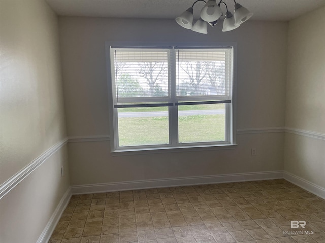 spare room with baseboards and a notable chandelier