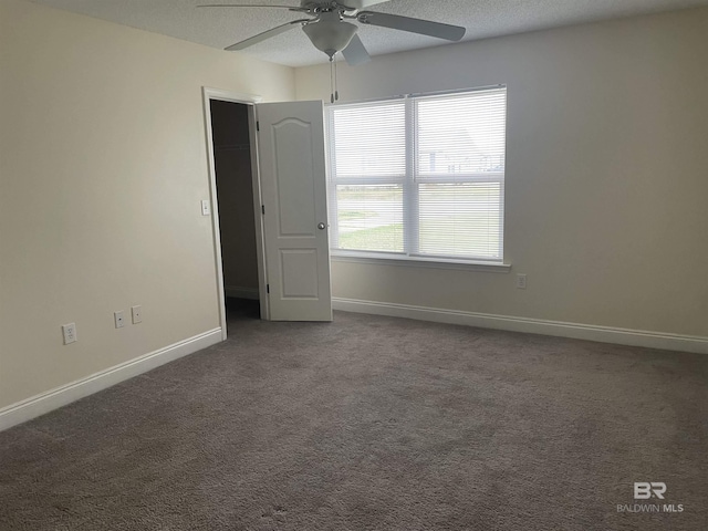 empty room with carpet floors, a textured ceiling, and baseboards